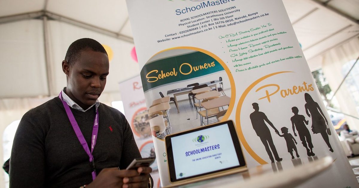 Man checking his phone beside a tablet at a business exhibition stand in Nairobi