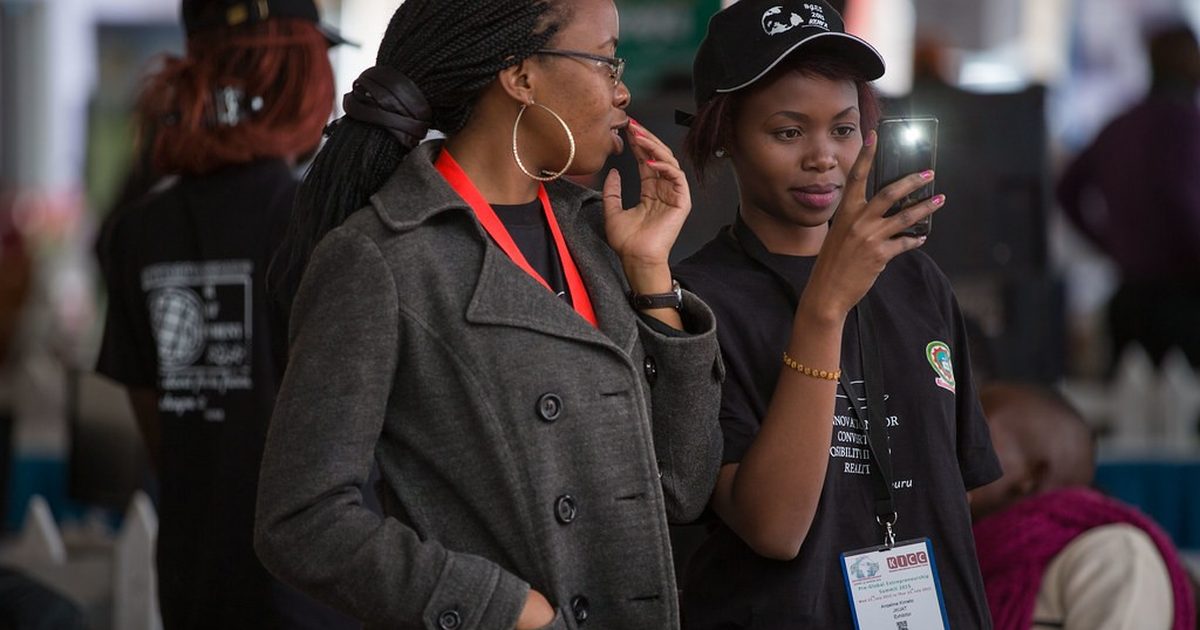 Two young women checking messages on their phones at an event in Nairobi