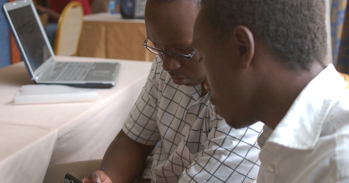 Two colleagues reviewing a message on a phone next to a laptop