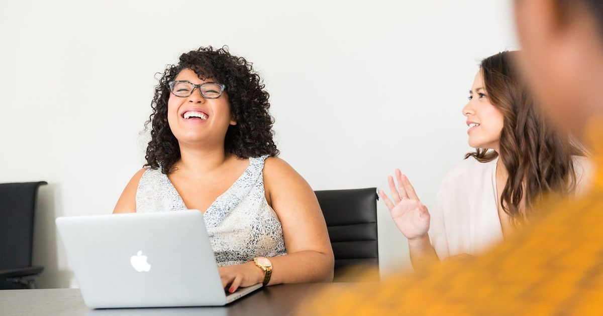 Two women laughing during a meeting with a laptop