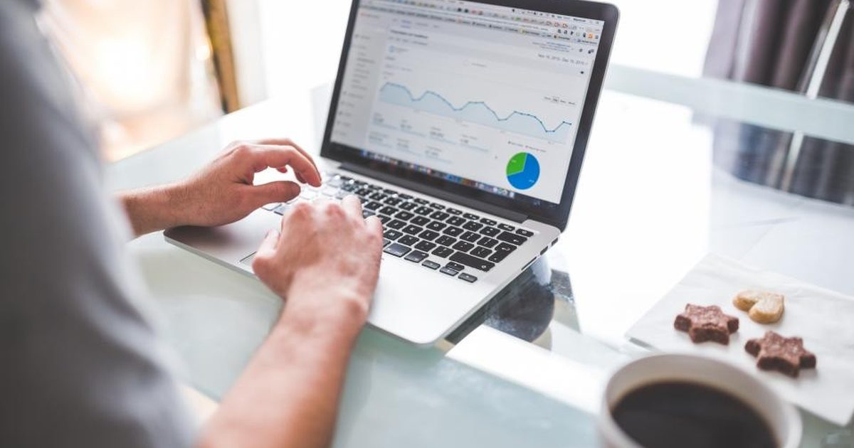 Person reviewing analytics charts on a laptop with a cup of coffee