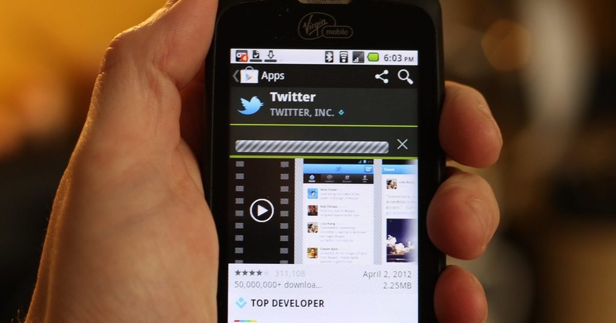 Hand holding an Android phone showing the Google Play app store